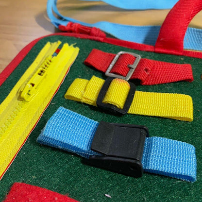 Montessori busy book for toddlers with buckles, zippers and laces for screen-free play. Supports development of fine motor skills.